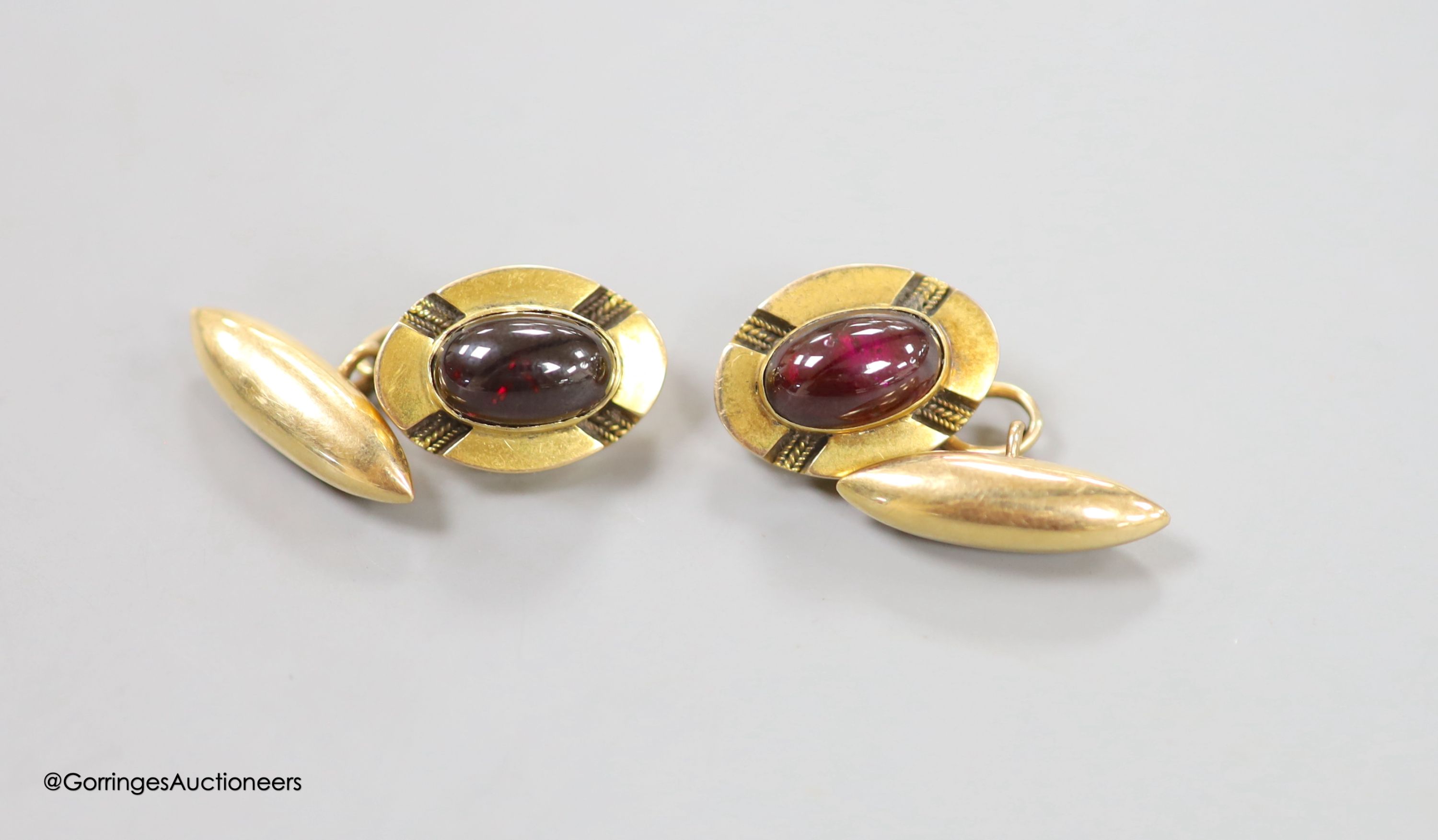 A pair of yellow metal and cabochon garnet set oval cufflinks, 18mm, gross weight 10.7 grams.